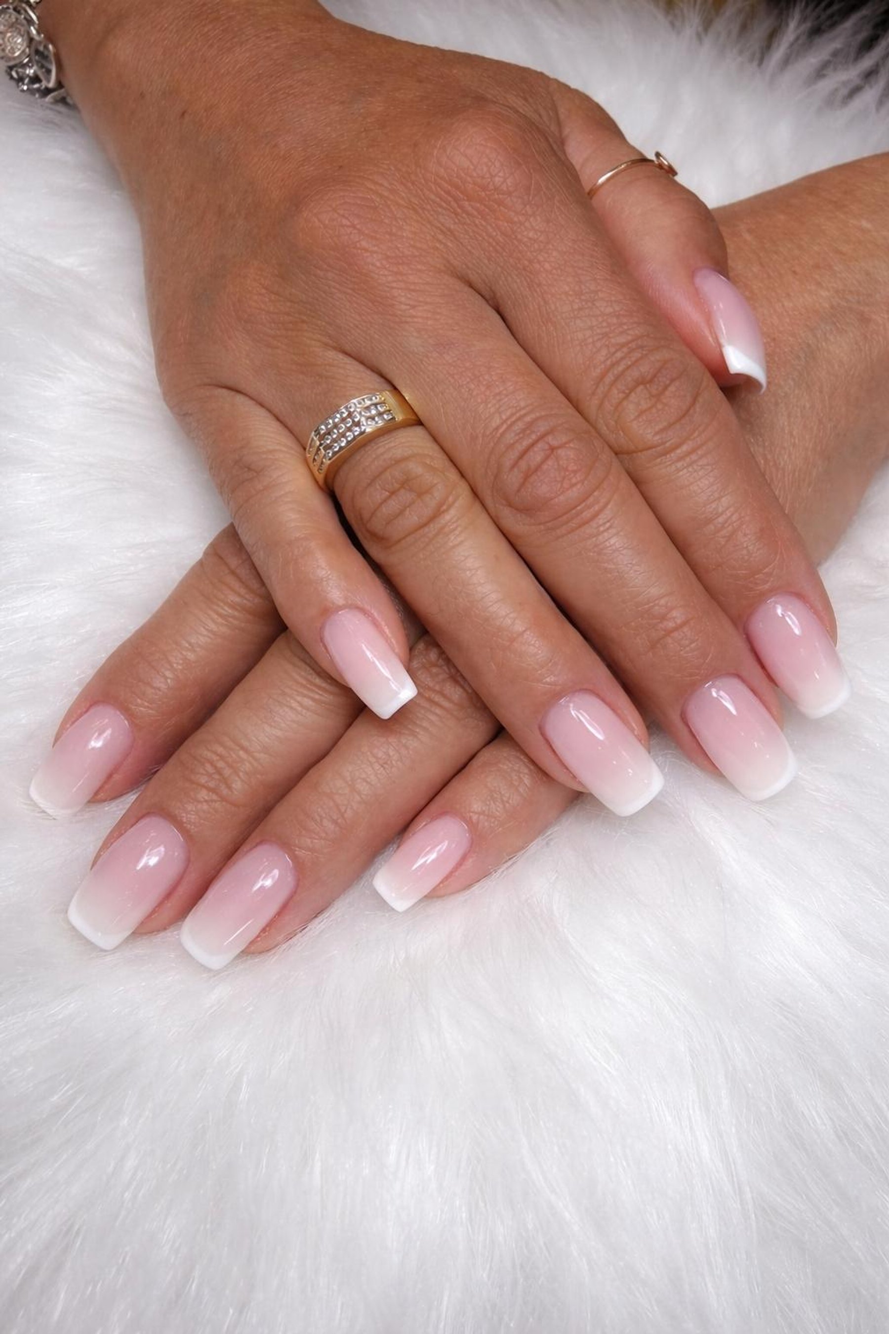 Soft pink to white ombré on square nails, hands resting on white fur
